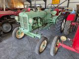un tracteur vert dans un garage avec d'autres tracteurs