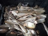 a lot of silver spoons and forks in a basket