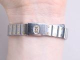 a woman ' s hand holding a silver bracelet with a cross on it