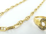 un gros plan sur un collier en or et une bague posés sur une surface blanche