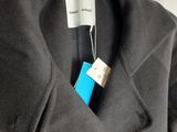 a grey coat hanging on a hanger with a tag on it