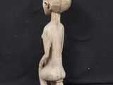 a wooden statue of a woman sitting on a stool