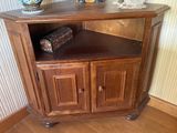 une petite armoire d'angle avec une porte en bois et un vase posé dessus