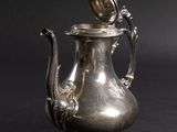 an antique silver tea pot with a lid on a black background