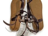sandales en cuir avec des lanières marron sur fond blanc, accompagnées d'une étiquette de prix