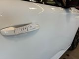 the door handle of a white car with a sticker on it
