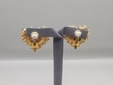 a pair of gold and pearl heart shaped earrings on a stand