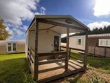 deux mobil-homes situés dans un espace verdoyant, avec des arbres en arrière-plan