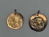 deux pendentifs en forme de pièces d'or représentant le visage d'un homme et d'une femme