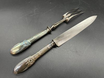 paire de couteaux anciens plaqués argent posés sur un fond noir