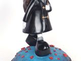 figurine of a woman in a black coat with a red rose in her hand