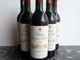 four bottles of red wine are lined up on a table