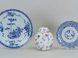 trois assiettes bleues et blanches et un petit vase posés sur une table