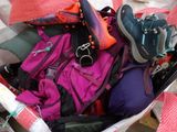 un sac rempli de sacs à dos et de chaussures posé sur un lit