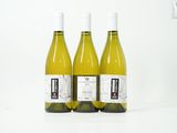 trois bouteilles de vin blanc posées les unes à côté des autres sur une table