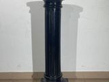black marble pedestal on tiled floor with white wall in background