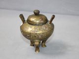 a small brass teapot with a lid on a table