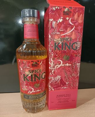 La bouteille de « Spice King » se trouve à côté de la boîte, sur la table.