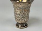 un vase en argent posé sur une table, dans lequel se trouve une bougie