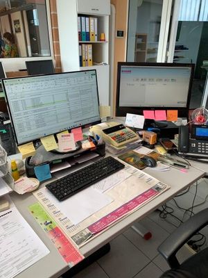 un bureau sur lequel se trouvent un ordinateur, un clavier, un écran et d'autres objets