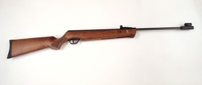 un fusil posé sur une surface blanche, avec une crosse noire