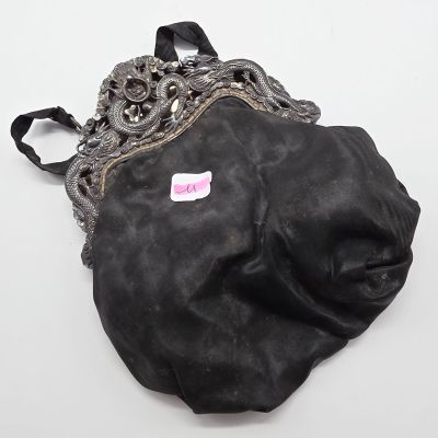 un vieux sac à main noir orné d'un autocollant rose, posé sur une surface blanche