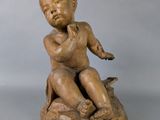 statue of a boy sitting on a rock with a bird in his hand