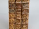 three old books sitting on top of each other on a white surface