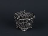 an ornate silver box with flowers and leaves on a black background
