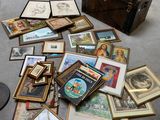 a pile of framed pictures on the floor next to a trunk