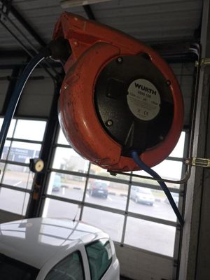 une photo d'une voiture dans un garage, avec un tuyau raccordé au plafond