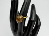 black mannequin hand holding a ring with a citrine stone on it