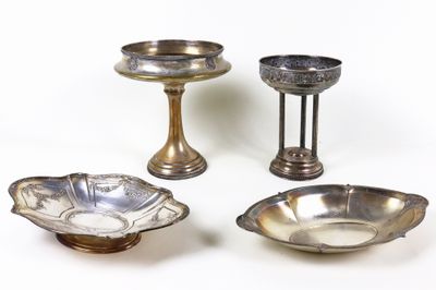 trois bols en métal argenté et un bougeoir posés sur une surface blanche