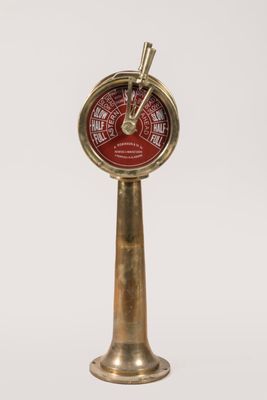 une horloge ancienne en laiton avec un cadran rouge sur fond blanc