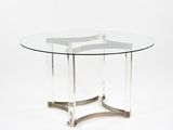 une table ronde en verre avec un piètement en métal et un plateau en verre transparent