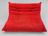 un fauteuil-futon rouge sur lequel est posé un oreiller