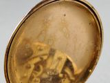 a gold pocket watch sitting on a white surface