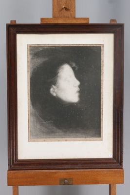 Une vieille photo représentant le visage d'une femme est exposée dans un cadre en bois.