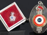 deux boutons de manchette argentés et rouges, accompagnés d'un coffret rouge et d'un insigne argenté et rouge
