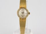 an image of a gold wrist watch on a clear glass stand