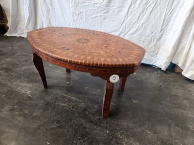 a wooden table with a woven top on a cement floor