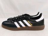 Les baskets adidas sont noires et blanches, avec une semelle marron.
