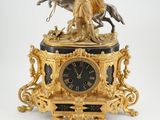 une horloge en or surmontée d'une statue représentant un homme à cheval