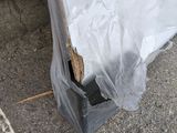 a plastic bag on the ground next to a piece of wood