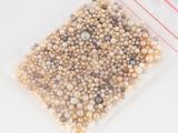a bag of pearls on a white table with a red ribbon