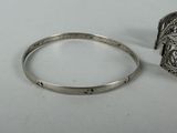 a silver bracelet and a silver ring on a white surface