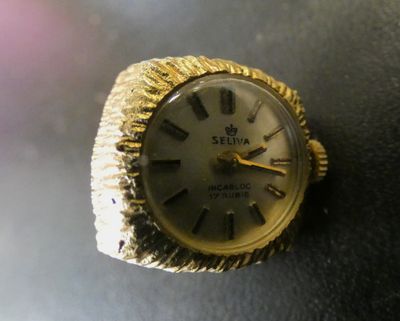 une bague en or sur laquelle est posée une montre, posée sur une table