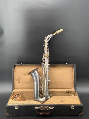 un vieux saxophone posé dans une valise, sur une surface noire
