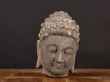 statue of a buddha head on a wooden table against a black background