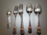 five silver spoons and two silver spoons on a table